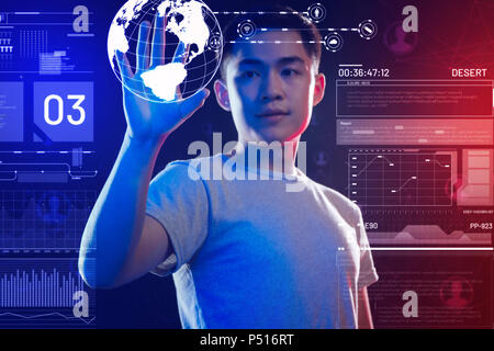 Jeune programmeur tenant un hologramme de la terre et réaliste à le regarder Banque D'Images