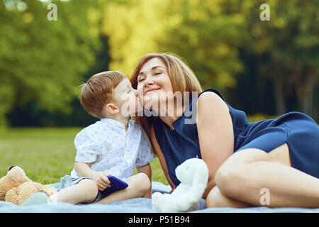 Mère avec enfant jouant sur l'herbe au coucher du soleil en été Banque D'Images