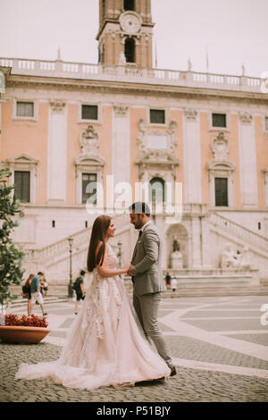 Young attractive couple nouvellement marié la marche et posant dans Rome avec belle architecture ancienne et sur l'arrière-plan le jour de leur mariage Banque D'Images