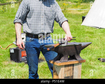 Un forgeron man working on metal sur l'enclume dans le jardin. Banque D'Images