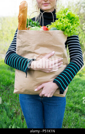 Belle jeune femme portant un sac d'épicerie en papier. Image recadrée. Banque D'Images