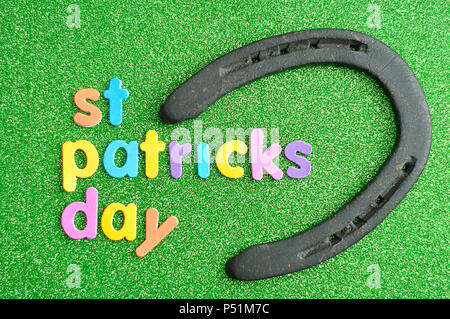 Heureux saint Patricks day en lettres colorées sur un fond vert avec un fer à cheval Banque D'Images