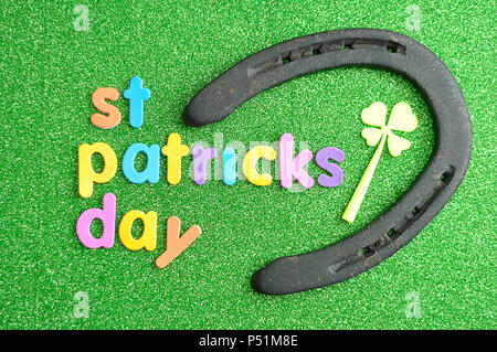 Heureux saint Patricks day en lettres colorées sur un fond vert avec un fer à cheval et un trèfle Banque D'Images