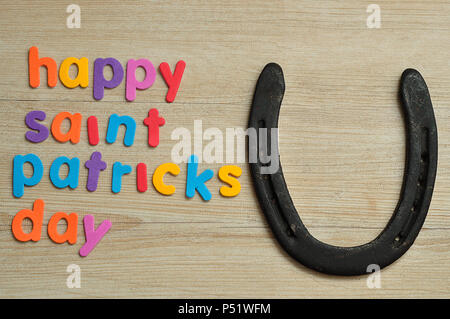 Heureux saint Patricks day en lettres colorées sur un fond de bois avec un fer à cheval Banque D'Images