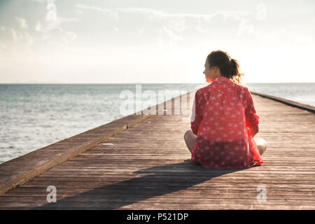 Pensive young woman tourist profiter de sa vie assis sur pier beach avec l'infini voir copy space Banque D'Images