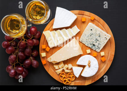 Fromage dégustation de vin, les bretzels, les raisins et les noix sur fond sombre, vue du dessus. La nourriture pour le vin. Banque D'Images