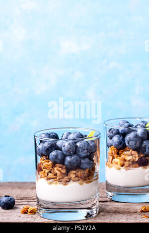 Blueberry dessert, gâteau au fromage, bagatelle, du muesli dans un verre sur une table en bois vintage avec des fissures. Banque D'Images