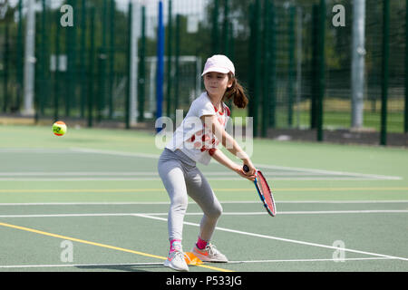 Session d'entraînement de tennis pour enfants / leçon ayant lieu sur un court de tennis avec les enfants / kids et entraîneur de tennis professionnel, en été. UK. (99) Banque D'Images