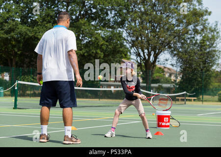 Session d'entraînement de tennis pour enfants / leçon ayant lieu sur un court de tennis avec les enfants / kids et entraîneur de tennis professionnel, en été. UK. (99) Banque D'Images