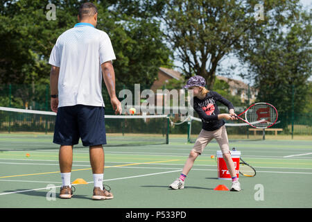 Session d'entraînement de tennis pour enfants / leçon ayant lieu sur un court de tennis avec les enfants / kids et entraîneur de tennis professionnel, en été. UK. (99) Banque D'Images