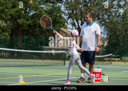 Session d'entraînement de tennis pour enfants / leçon ayant lieu sur un court de tennis avec les enfants / kids et entraîneur de tennis professionnel, en été. UK. (99) Banque D'Images