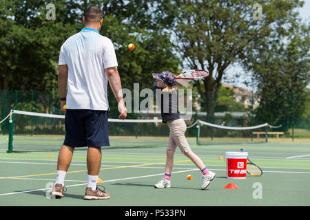 Session d'entraînement de tennis pour enfants / leçon ayant lieu sur un court de tennis avec les enfants / kids et entraîneur de tennis professionnel, en été. UK. (99) Banque D'Images