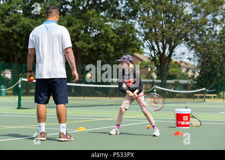 Session d'entraînement de tennis pour enfants / leçon ayant lieu sur un court de tennis avec les enfants / kids et entraîneur de tennis professionnel, en été. UK. (99) Banque D'Images