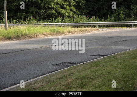 Mauvais revêtement routier sur les routes de la Grande-Bretagne. La sortie de rond-point et un Pyebush355, Beaconsfield. Face à SSW. Banque D'Images