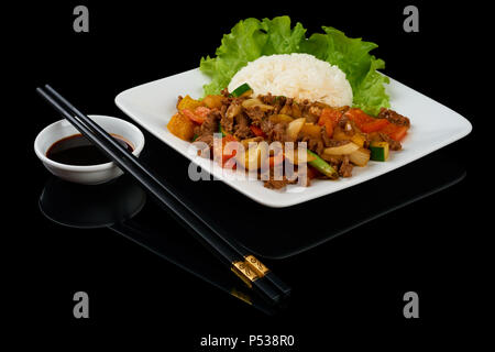 Plat vietnamien Bo Luc Lac (faire sauter les dés de boeuf) est un boeuf en cubes sauté aux concombres, tomates, oignons rouges, poivre et sauce de soja. Isolated on black Banque D'Images