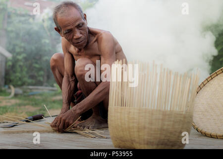 Vieil homme tisse des paniers en bambou et à la campagne. Banque D'Images