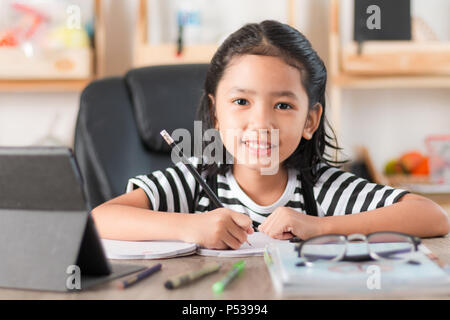 Petite fille asiatique à faire des devoirs et en pointant le doigt sur table en bois sélectionner focus profondeur de champ Banque D'Images