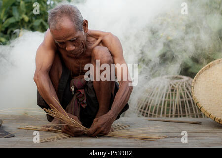 Vieil homme tisse des paniers en bambou dans la campagne. Banque D'Images