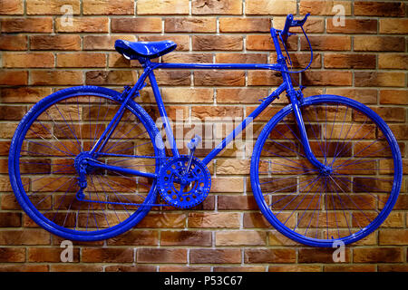 Vélo bleu sur un mur de briques. Rare beau tons roses. Banque D'Images