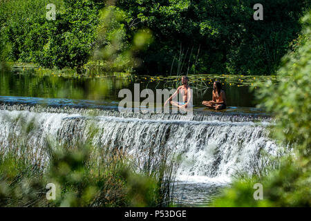 Deux hommes méditer dans l'eau à Warleigh Weir sur la rivière Avon près de Bath dans le Somerset sur une chaude journée d'été. Banque D'Images
