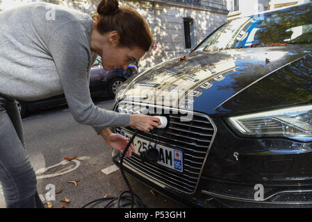 9 octobre 2015 - Paris, France : Pauline Lebreton relie sa voiture électrique hybride à une station de recharge Autolib'. Propriétaire de voitures électriques sont autorisés à utiliser la station Autolib' à leur charge des batteries électriques. C'est moins cher pour un Parisien de payer pour les frais de charge électrique Autolib' (1 euro par heure) que de payer le stationnement. Pauline Lebreton connecte son véhicule hybride a une station Autolib' afin de charger sa batterie. Banque D'Images