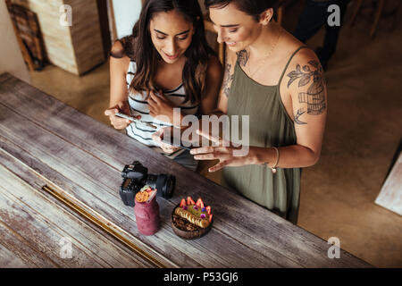 Les blogueurs alimentaire prise de photos pour leur blog en utilisant les téléphones mobiles. Photos de tournage blogueurs femmes coupe de fruits et jar smoothie placés le long d'une Banque D'Images