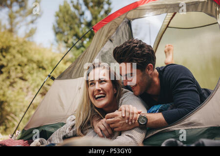 Smiling young couple couché dans une tente. Heureux couple aimant se reposer à l'intérieur d'une tente de camping. Banque D'Images