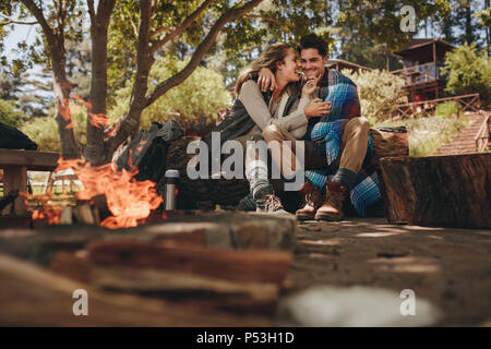 Camping romantique couple par feu en plein air. Aimer l'homme et la femme se reposer près de camp. Banque D'Images