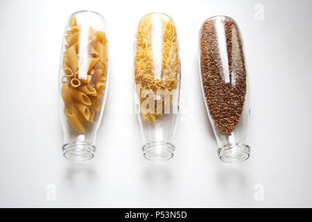Penne Rigate, pâtes aux œufs et de sarrasin est stocké dans une bouteille en verre transparent isolé sur fond blanc Banque D'Images