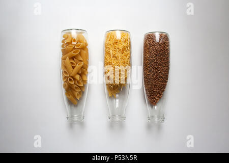 Penne Rigate, pâtes aux œufs et le sarrasin dans des contenants en verre transparent isolé sur fond blanc d'un high angle view Banque D'Images
