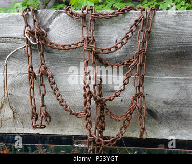 Old rusty usés des chaînes de pneu de traction dans la neige et la glace accroché sur le côté en bois sur un camion dans les Adirondacks, NY USA Banque D'Images