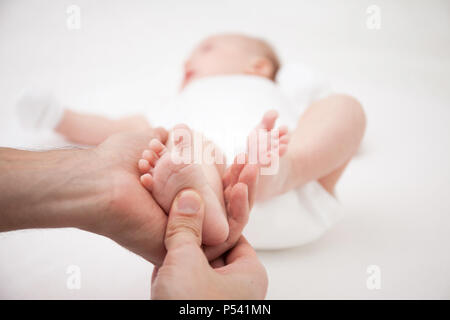 Massage de pied mère pour son nouveau-né. Isolé sur fond blanc. Banque D'Images