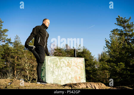 Caucasian Male boxer moyen-âge la formation en dehors de la nature. Belle journée d'hiver ensoleillée dans la forêt avec ciel bleu. Le port de vêtements de sport noir Banque D'Images