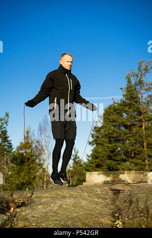 Caucasian Male boxer moyen-âge la formation en dehors de la nature. Belle journée d'hiver ensoleillée dans la forêt avec ciel bleu. Le port de vêtements de sport noir Banque D'Images