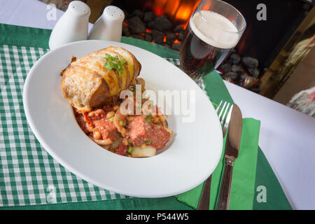 Une partie de Corned Beef hash servi avec un fromage surmontée de pommes de terre Hasselback Banque D'Images