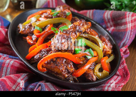 Ailes de poulet chinois avec des légumes dans une sauce aigre-douce sur un plat chaud Banque D'Images