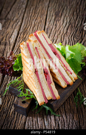 Club sandwich - panini au jambon et fromage sur fond de bois. Nourriture pique-nique. Banque D'Images