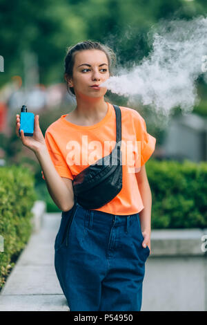 Jolie jeune fille vape portables populaires,gadget vaping device.Happy brunette fille vaper avec e-cig.Portrait de fumeur modèle féminin avec cigarett électronique Banque D'Images