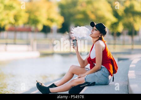 Jolie jeune fille asiatique vape portables populaires,gadget vaping device.Happy brunette fille vaper avec e-cig.Portrait de fumeur modèle féminin avec ec électronique Banque D'Images