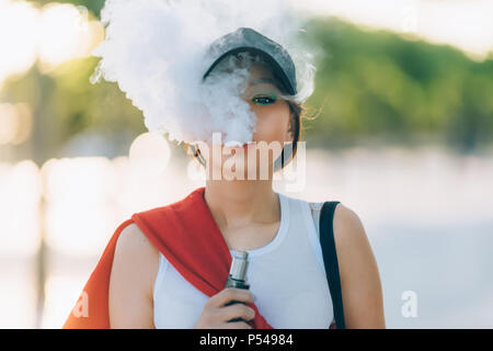 Jolie jeune fille asiatique vape portables populaires,gadget vaping device.Happy brunette fille vaper avec e-cig.Portrait de fumeur modèle féminin avec ec électronique Banque D'Images