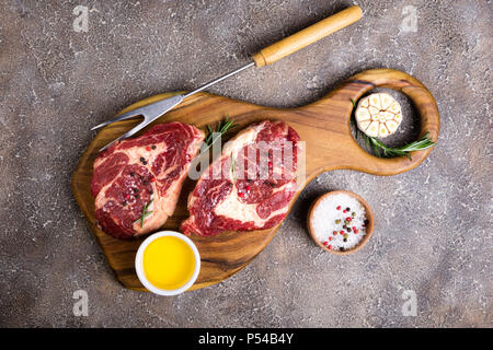 Steak de bœuf cru et les ingrédients sur une planche à découper. La viande crue. Vue d'en haut Banque D'Images