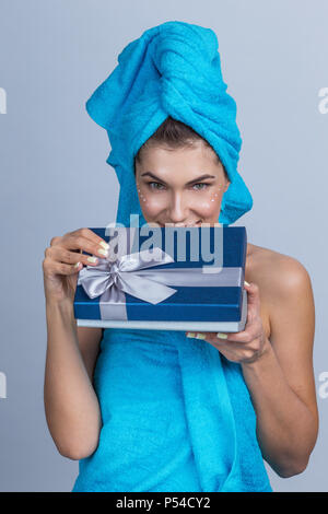 Belle femme avec des serviettes sur la tête l'application après la douche crème et holding gift box Banque D'Images