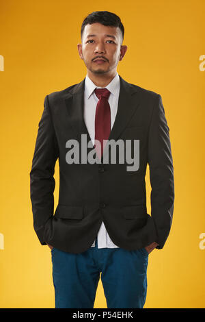 Asian business man with hands in pocket isolé sur fond jaune Banque D'Images