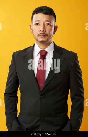 Portrait of young businessman with hands in pocket isolé sur fond jaune Banque D'Images