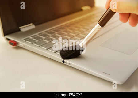 Clavier ordinateur Nettoyage et soin. Homme la main avec une brosse pour enlever la poussière de la clavier. nettoyage du clavier de l'Ultrabook gris moderne tra Banque D'Images