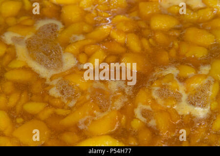 Les pêches d'été frais coupé en morceaux et le sucre en ébullition et de pectine pour faire de la confiture de pêches fraîches faites maison. Close up. Banque D'Images
