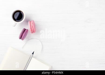 Une tasse de café, ordinateur portable deux macarons et un crayon sur la table en bois. Vue de dessus, à la verticale. Banque D'Images