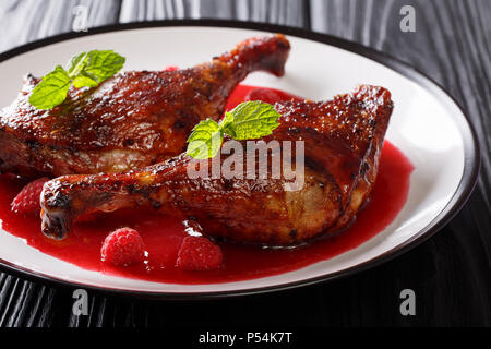 Les aliments biologiques : cuisses de canard poêlé servi avec sauce aux framboises et menthe fraîche sur une plaque sur la table horizontale. Banque D'Images