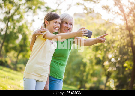 Grand-mère et petite-fille prennent des photos dans le parc. Banque D'Images