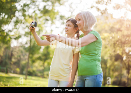 Grand-mère et petite-fille prennent des photos dans le parc. Banque D'Images